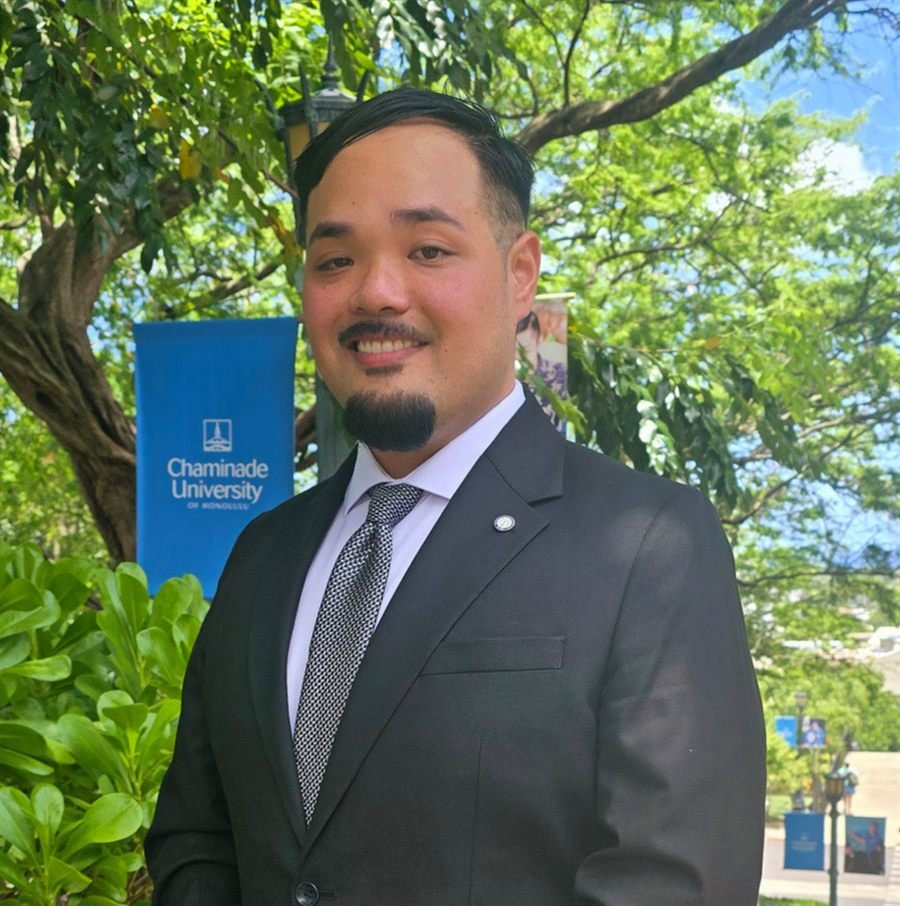 Dr. Alexander Seto in a dark suit, smiling outdoors at Chaminade University of Honolulu